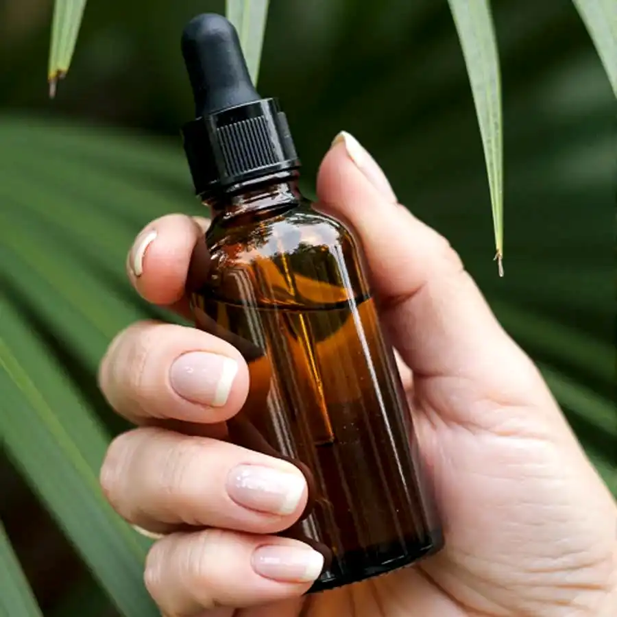 Hand holding amber glass dropper bottle with essential oil or se